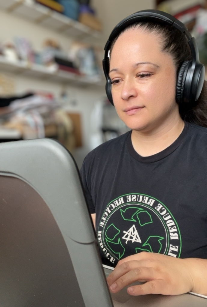 woman with headphones on sitting at a computer typing working on a website design