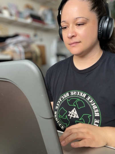 woman with headphones on sitting at a computer typing working on a website design