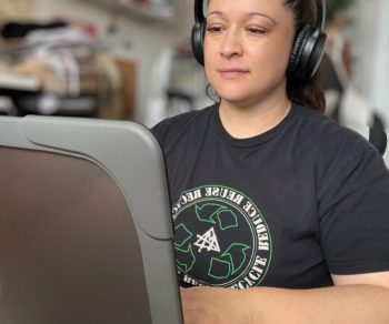 woman with headphones on sitting at a computer typing video editing